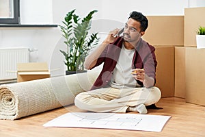 Man with blueprint and boxes moving to new home