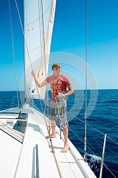 A man on board a sailing yacht at sea.