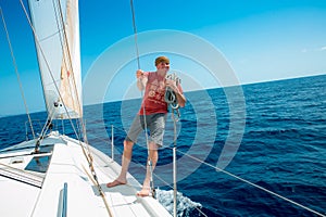 A man on board a sailing yacht at sea.
