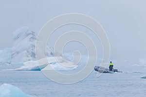 Man on a boat between bizarre ice floes of Iceberg lagoon jokulsarlon on the south of Iceland