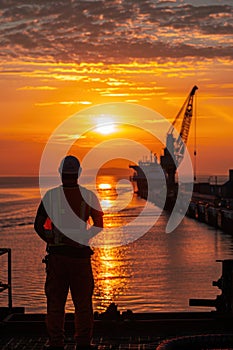 Man on boat views sunset over ocean, admiring water, sky, and afterglow