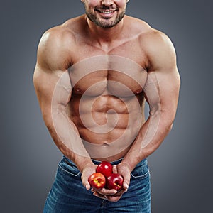 Man bodybuilder holding a fresh fruits