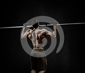 Man - bodybuilder perform exercise chin-up