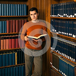 Man with a book standing in the vintage library shelves.