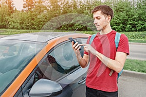 Man books a car or taxi on a smartphone in the carsharing app to get around the city. New generation chooses not to own a