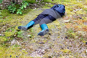 A man in boots lies in the forest on the grass. The concept of a lost person, dehydration. Copy space for text. Accident