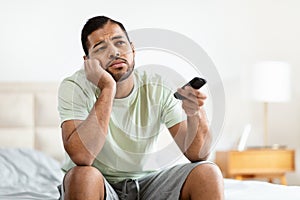 Man with bored expression holding remote