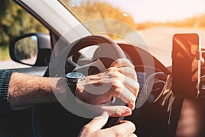 Man with both hands on steering wheel driving at sunset