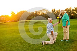 Man with bouquet is kneeling.