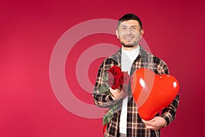 Man with a bouquet of red roses and a red heart-shaped balloon on a red background with side space. Cupidon on St photo