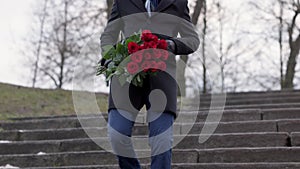 A man with a bouquet of roses on the street runs down the stairs Valentine's Day