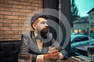Man in a bow tie. Confident bar customer sit in cafe and thinking. Date meeting of hipster awaiting in pub. Business on