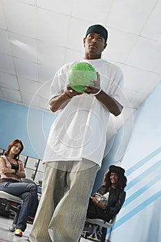 Man Bowling With Female Friends In Background