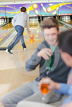 Man bowling while friends have drink