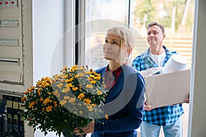 Man with box and woman with flowers entering new house