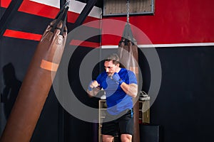 Man boxer exercising punches with boxing bag in gym, Boxer hitting a huge punching bag at a boxing studio
