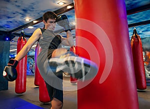 Man boxer hitting a huge punching bag at a boxing studio. Man boxer training hard. Thai boxer punch kick by punching bag, Black ba