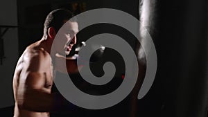 Man boxer making strikes on a boxing bag. Fighter training indoor