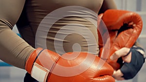 Man boxer putting red boxing gloves before fight training on box ring