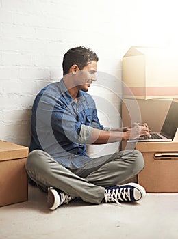 Man, boxes and laptop working in new home, house and residence for moving, relocating or buying property. Male person photo