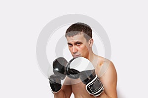 A man in boxing gloves with bruises on body and face stands in a rack during a fight and boxing on a white isolated background