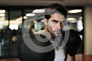 Man, boxing gloves and punch with gym for fitness, wellness or training for fight, performance or sport. MMA, boxer or