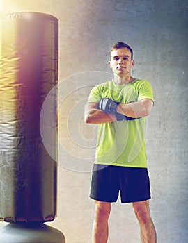 Man with boxing gloves and punching bag in gym