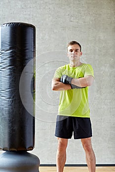 Man with boxing gloves and punching bag in gym