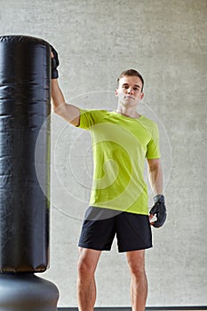 Man with boxing gloves and punching bag in gym