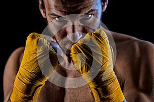 The man in boxing gloves. Young Boxer fighter over black background.