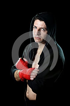 Man in boxing hoodie jumper with hood on head with wrapped hands wrists ready to fight