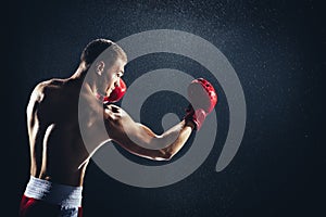 Man boxing with red gloves on his hands in the rain.