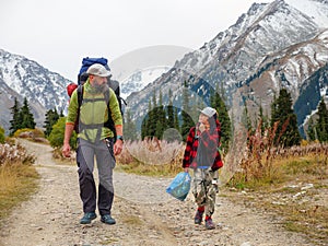 A man and a boy with backpacks walk along the road