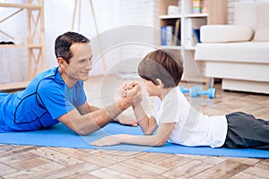 The man and the boy are engaged in arm-wrestling.