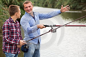 Man and boy fishing together on freshwater lake