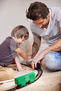 Man, boy and playing with train toys, together for family time and fun with plastic railway track at home. Father, child