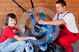 Man and boy preparing a cultivator machine for work
