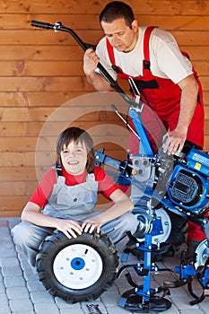 Man and boy servicing a cultivator machine