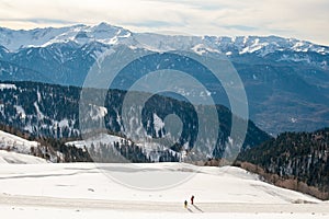 Man and boy are on snow road. Mountain landscape.