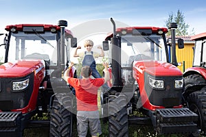 man and boy stand in front of large red new tractors at sales site