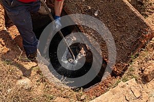 Man breaking apart a wastewater outlet in an old septic tank to bring it up to code