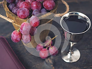 Man breaking the bread, with wine, grapes and Bible in the background