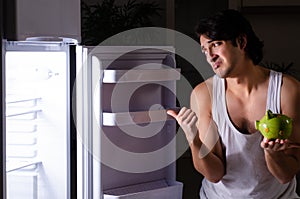 Man breaking diet at night near fridge