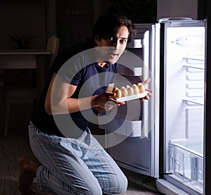 Man breaking diet at night near fridge