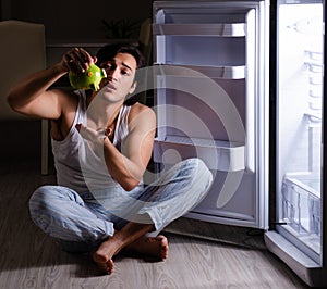 Man breaking diet at night near fridge