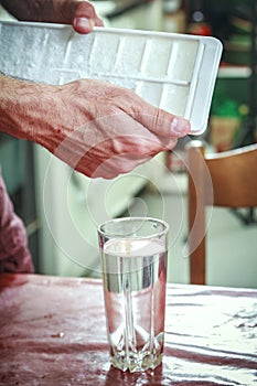 Man breaking the ice, cooling water in a glass