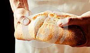 Man breaking a loaf of crusty white bread