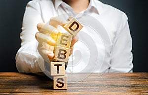 A man breaks a tower of blocks with the word Debts. Reduction or restructuring of debt. Bankruptcy. Refusal to pay. Heavily photo