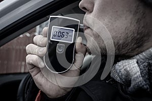 a man with a breathalyzer in the car