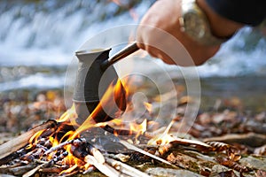 Man brewing coffee on bonfire